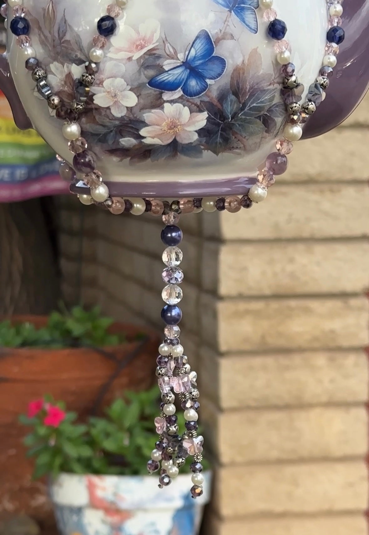 Jewel tail with purple and clear crystals holding a floral-patterned vase.